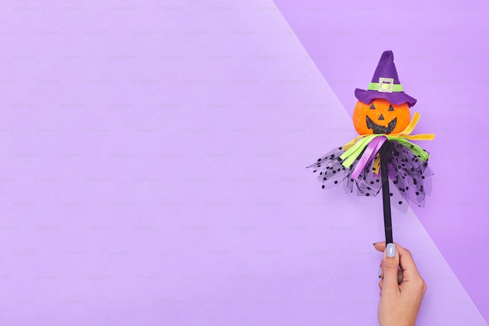 a hand holding a halloween decoration on a purple background
