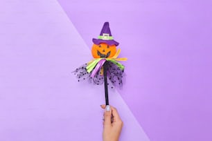 a hand holding a halloween decoration on a purple background