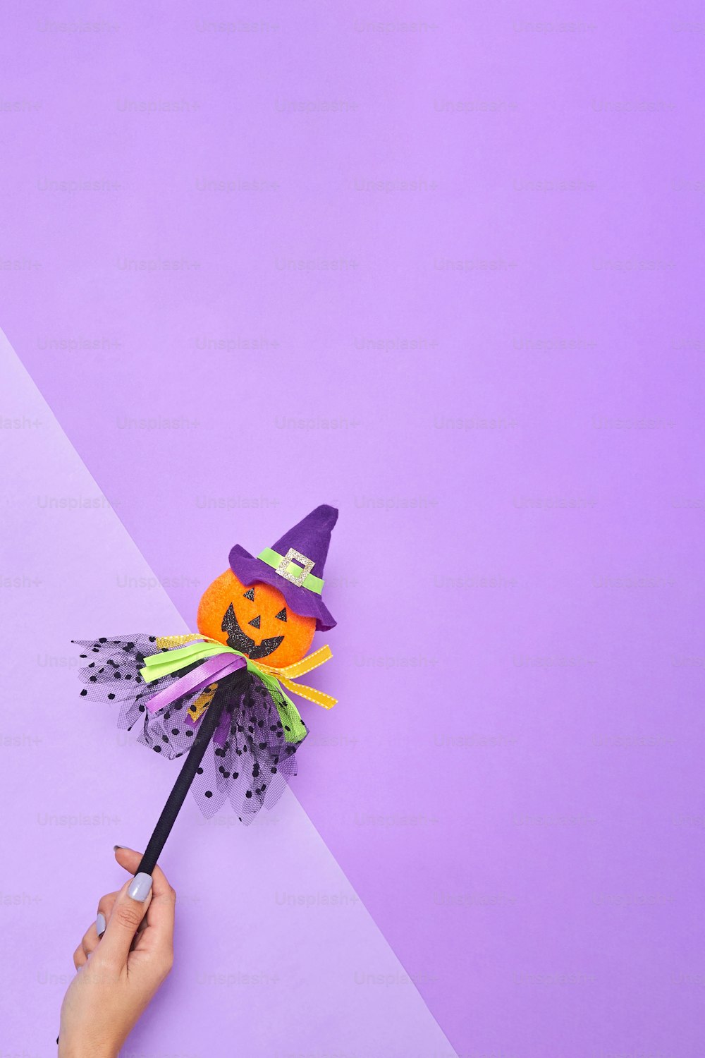 a person holding a broom with a halloween decoration on it