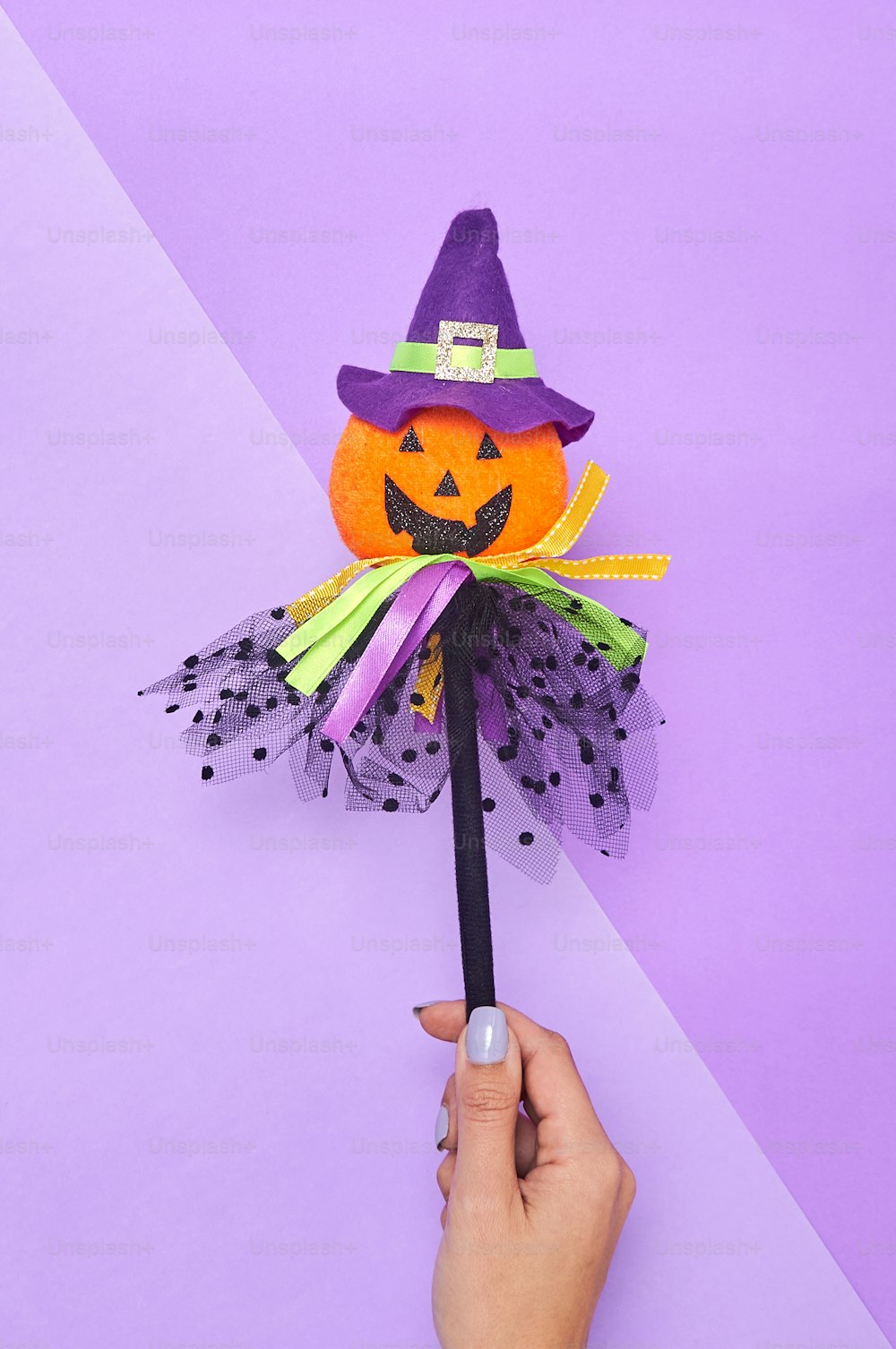 Une main tenant une décoration d’Halloween sur un fond violet