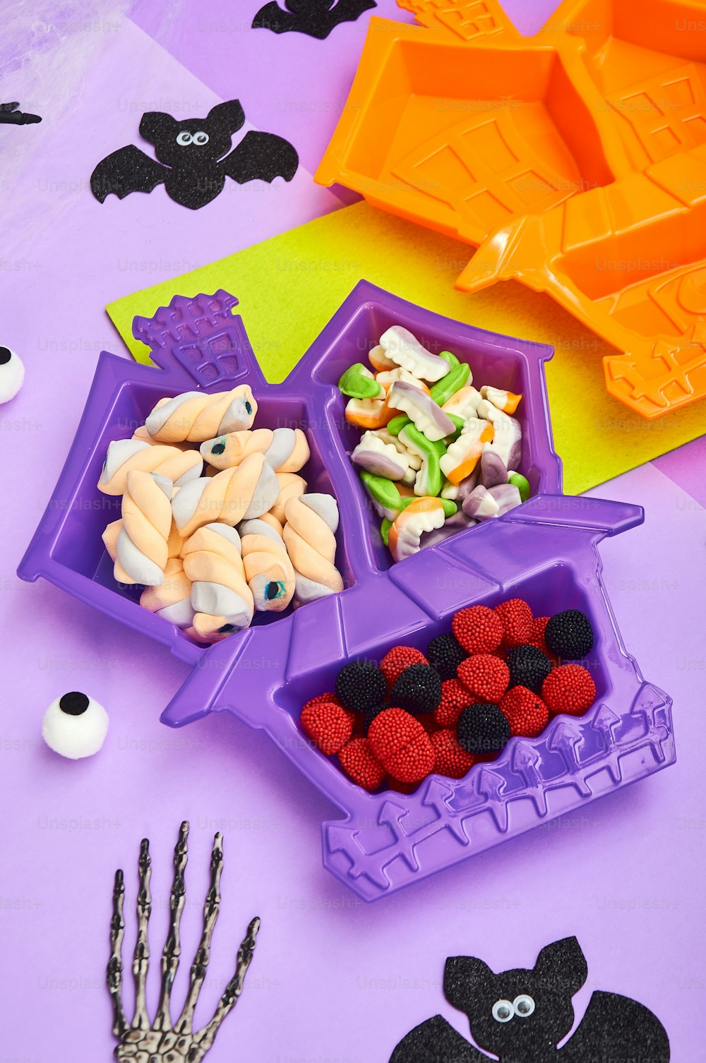 Ein Tisch mit lila Tabletts, gefüllt mit Halloween-Leckereien