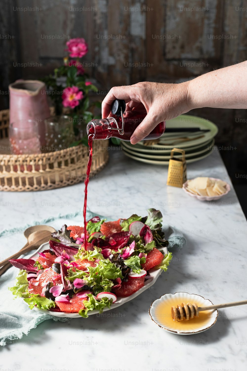 a person pouring dressing onto a plate of salad