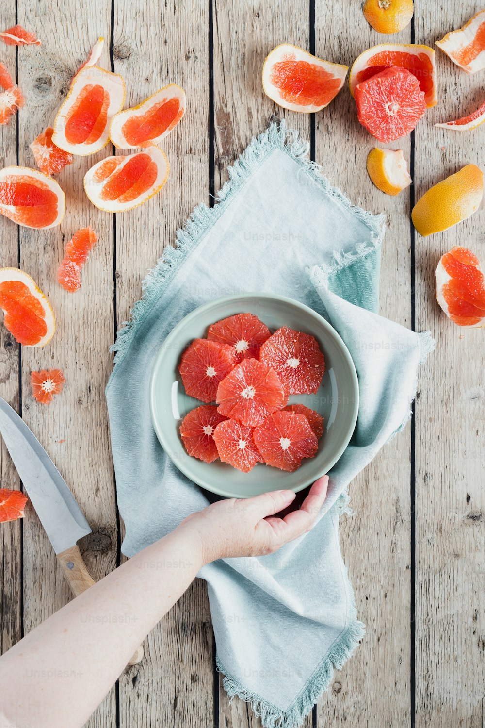 a person holding a plate of sliced grapefruits