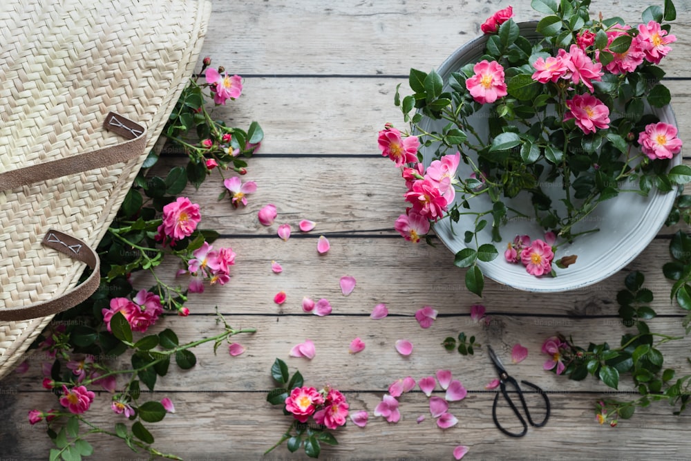 un panier de fleurs roses à côté d’une paire de ciseaux