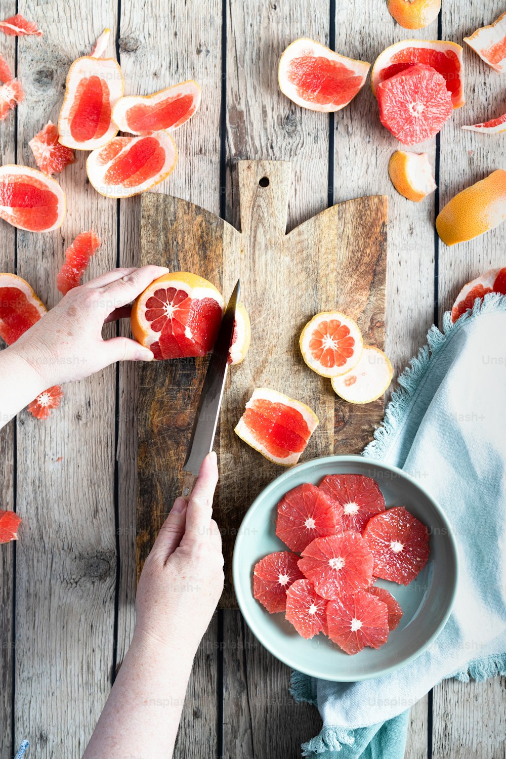 a person cutting up a grapefruit on a cutting board