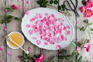 a white plate topped with pink flowers next to a bowl of honey