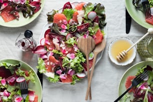 a table topped with plates of salad and a wooden spoon