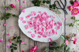 ein weißer Teller mit rosa Blumen auf einem Holztisch