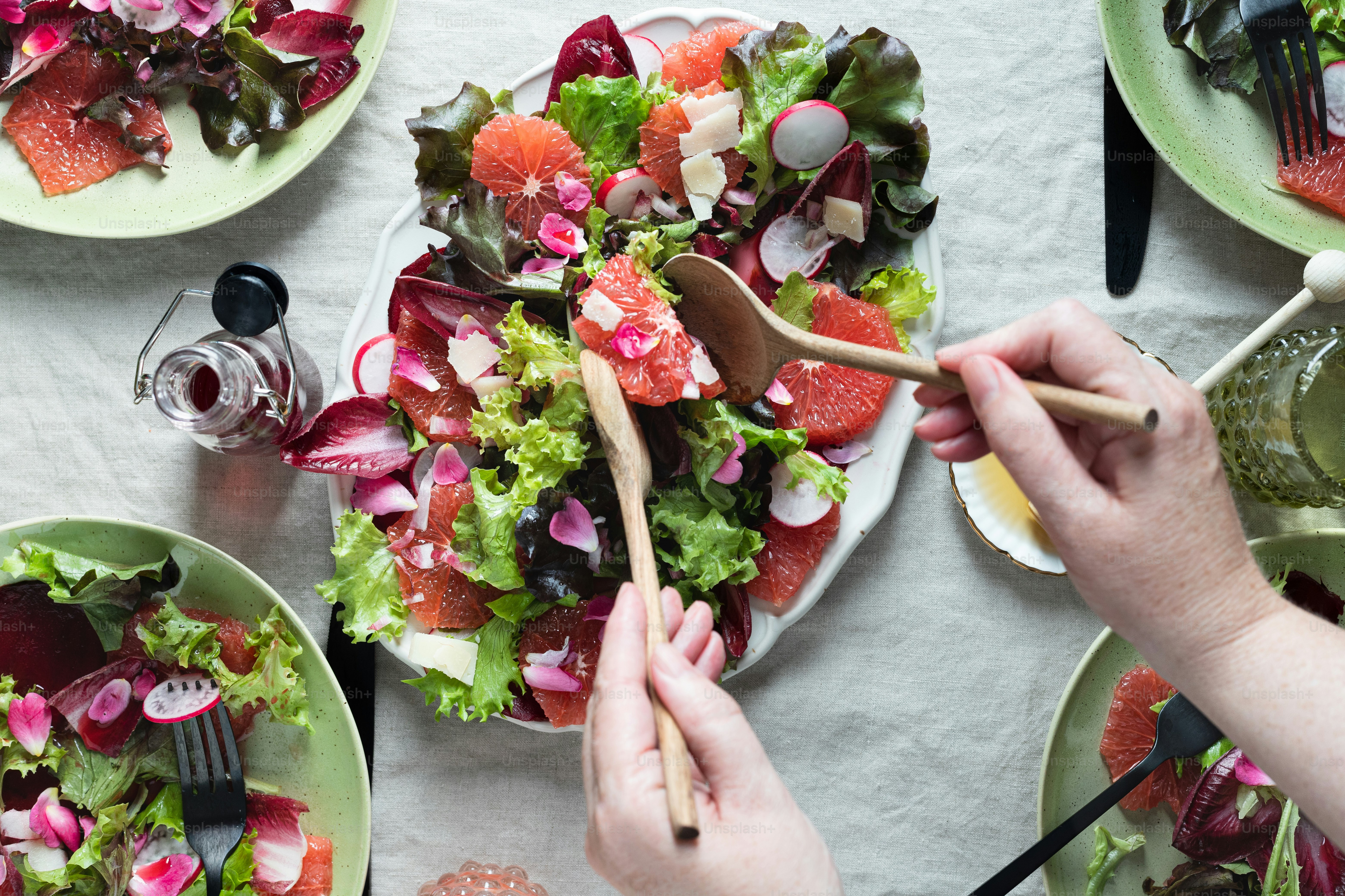 a table topped with plates of salad and utensils