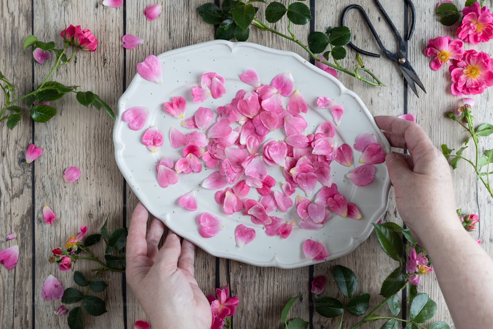 a person is decorating a cake with pink flowers