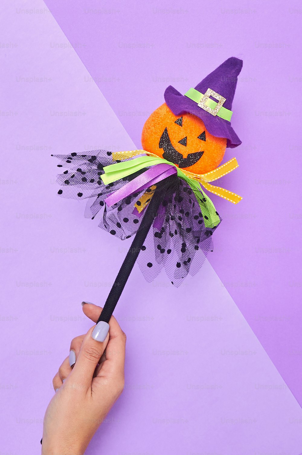 une main tenant un balai avec une décoration d’Halloween dessus