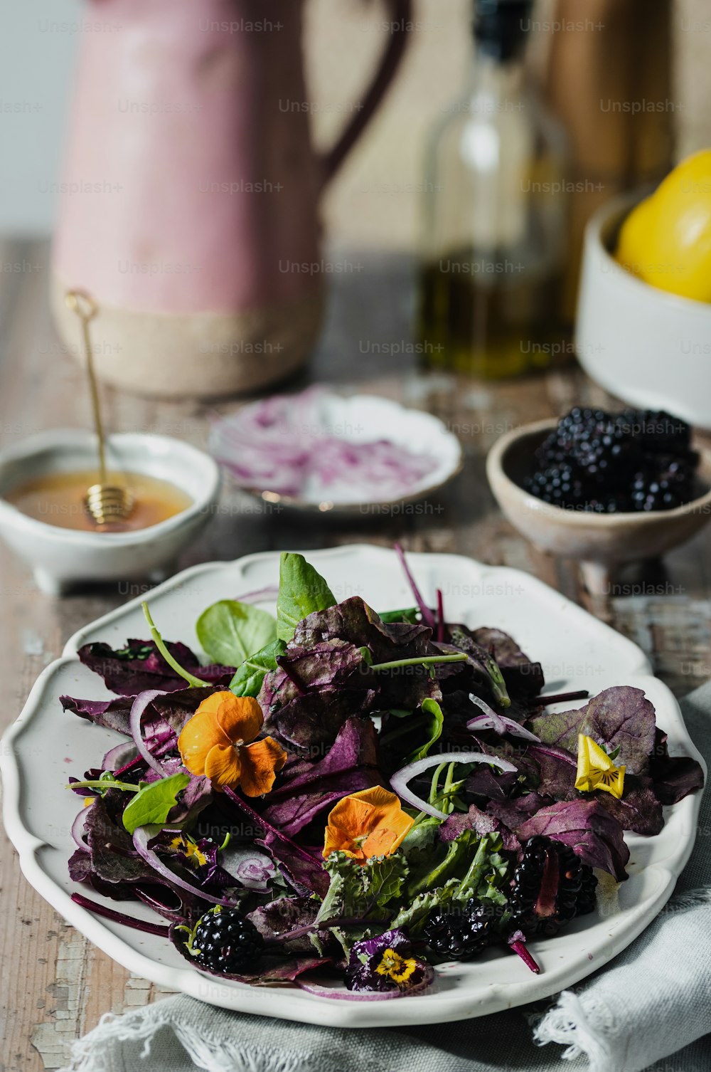 ein weißer Teller mit einem Salat neben einer rosa Vase