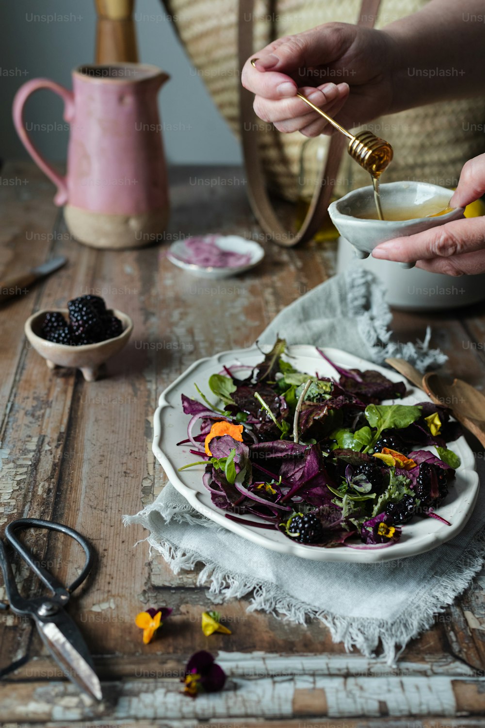 a woman is preparing a salad on a white plate