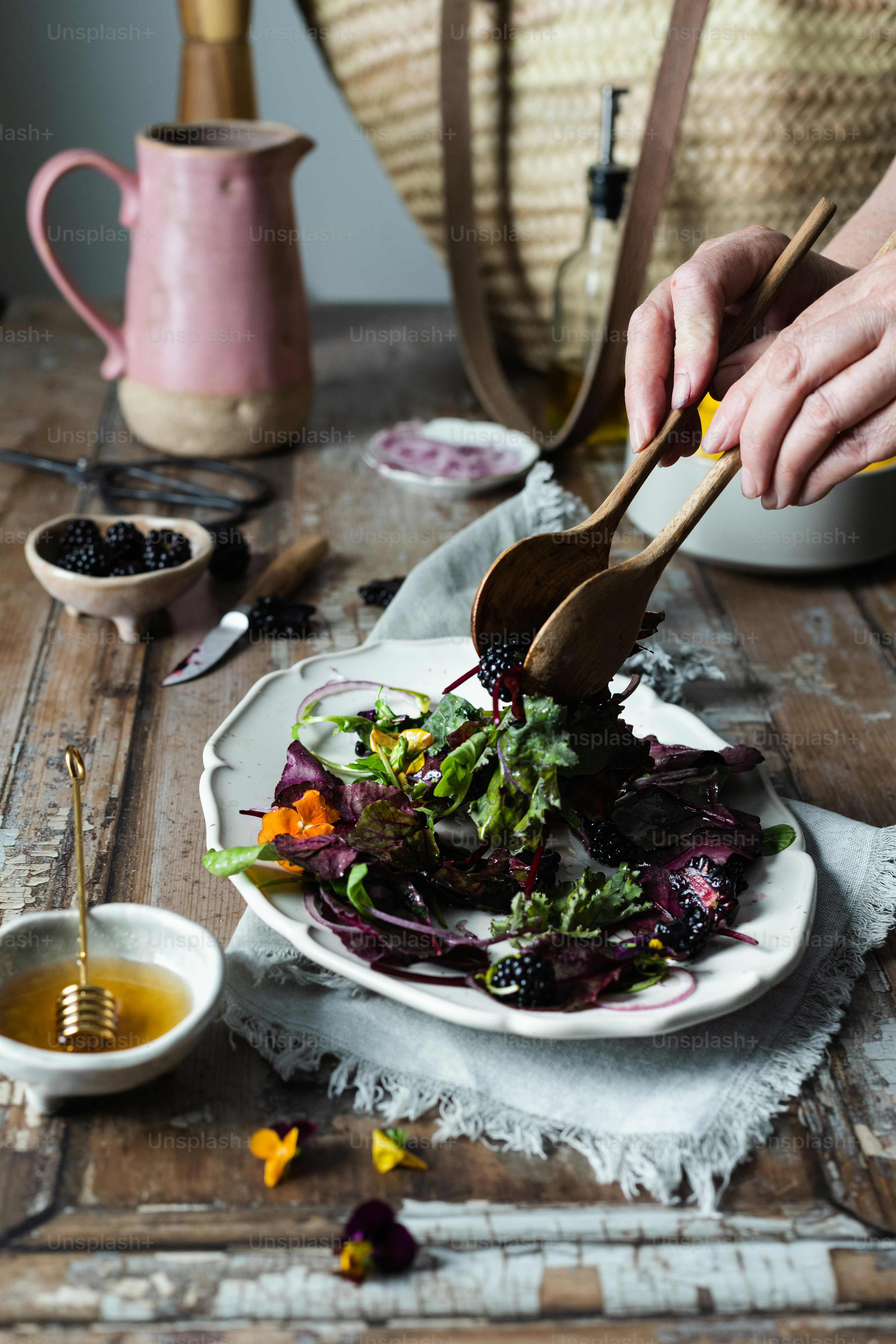a woman is cutting a salad on a plate