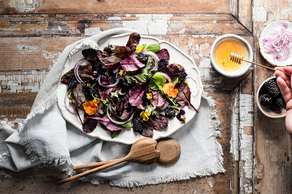 a person holding a spoon over a plate of salad