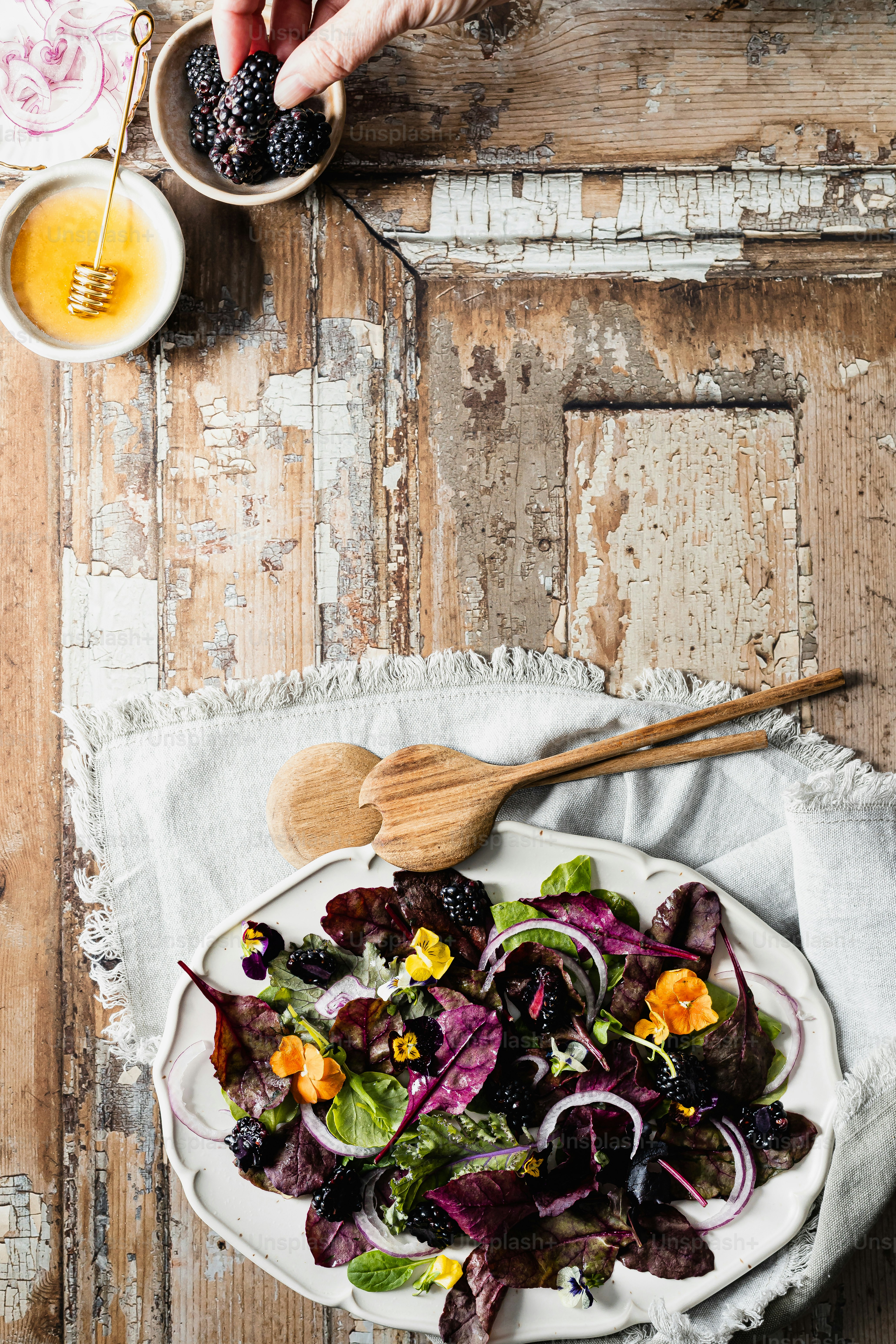 un plato blanco cubierto con una ensalada junto a un tazón de fruta