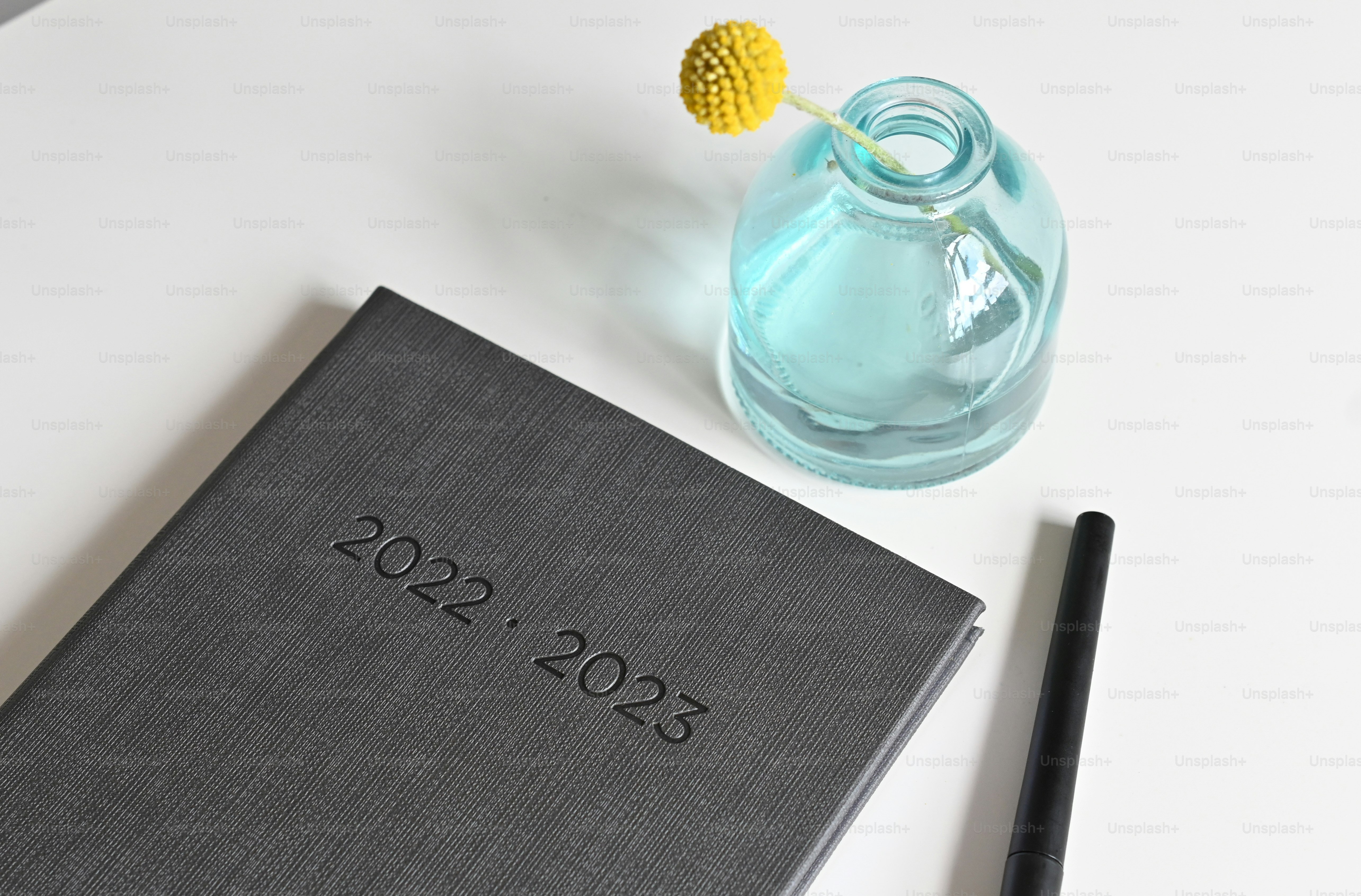 a blue vase with a yellow flower next to a book