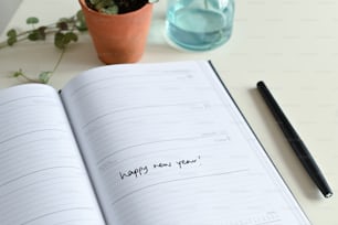 an open notebook with writing on it next to a plant