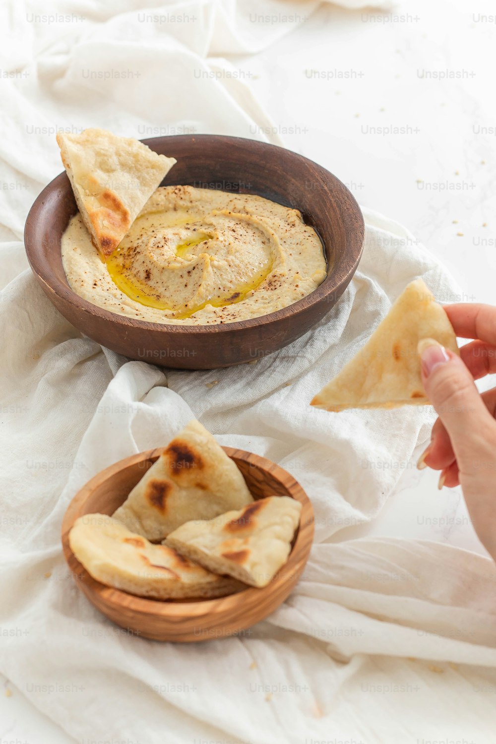 a bowl of hummus next to a bowl of pita bread