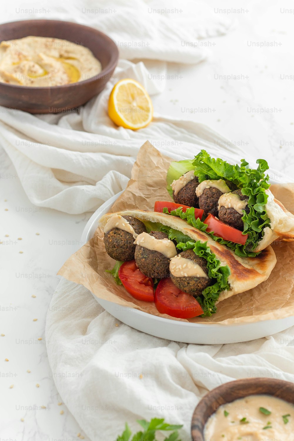 two pita sandwiches on a plate with a bowl of dip