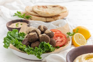 a plate of food with pita bread, tomatoes, lettuce, and