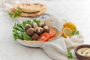 a bowl filled with meatballs and vegetables next to a plate of pita bread