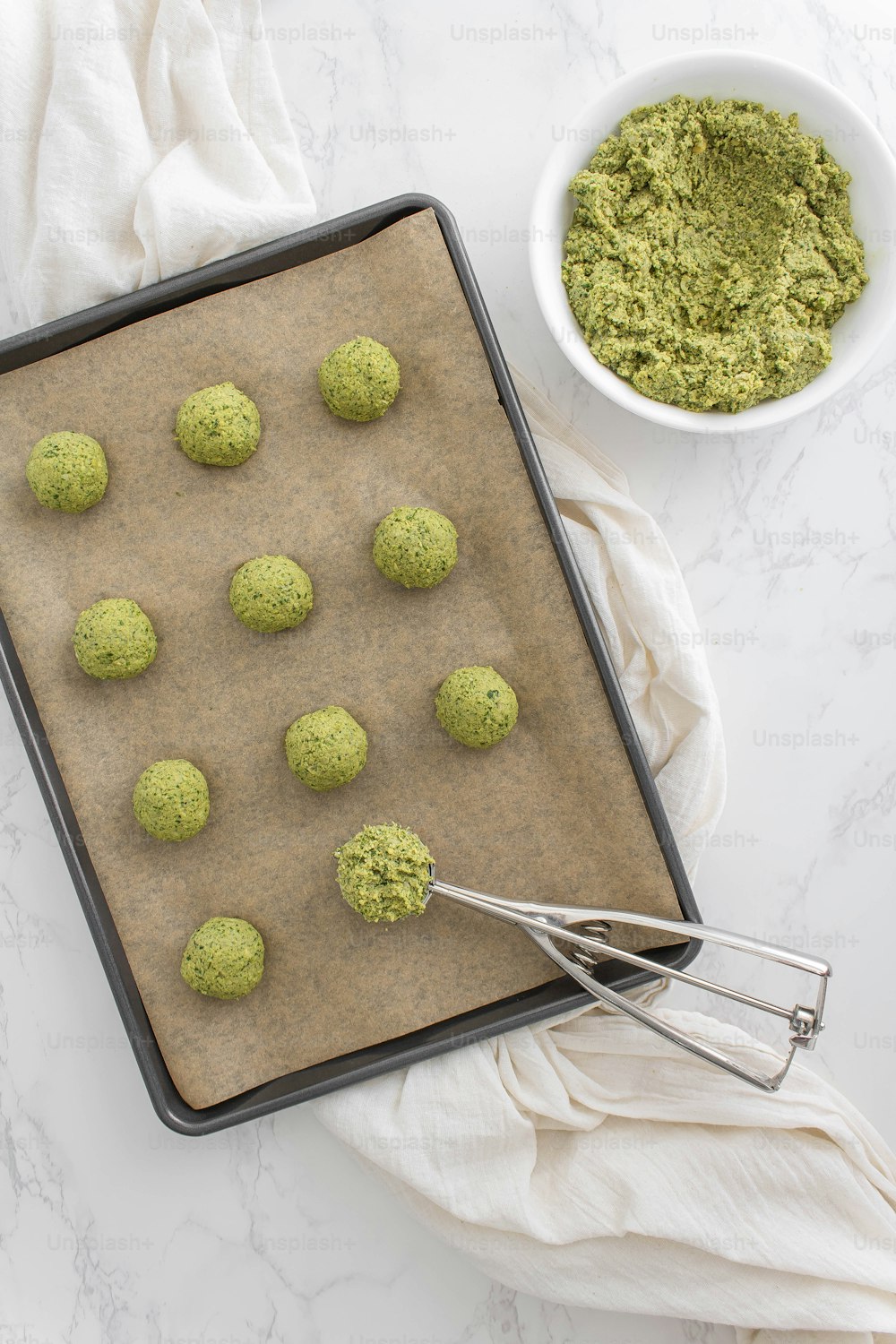 a cookie sheet with green cookies and a bowl of green powder