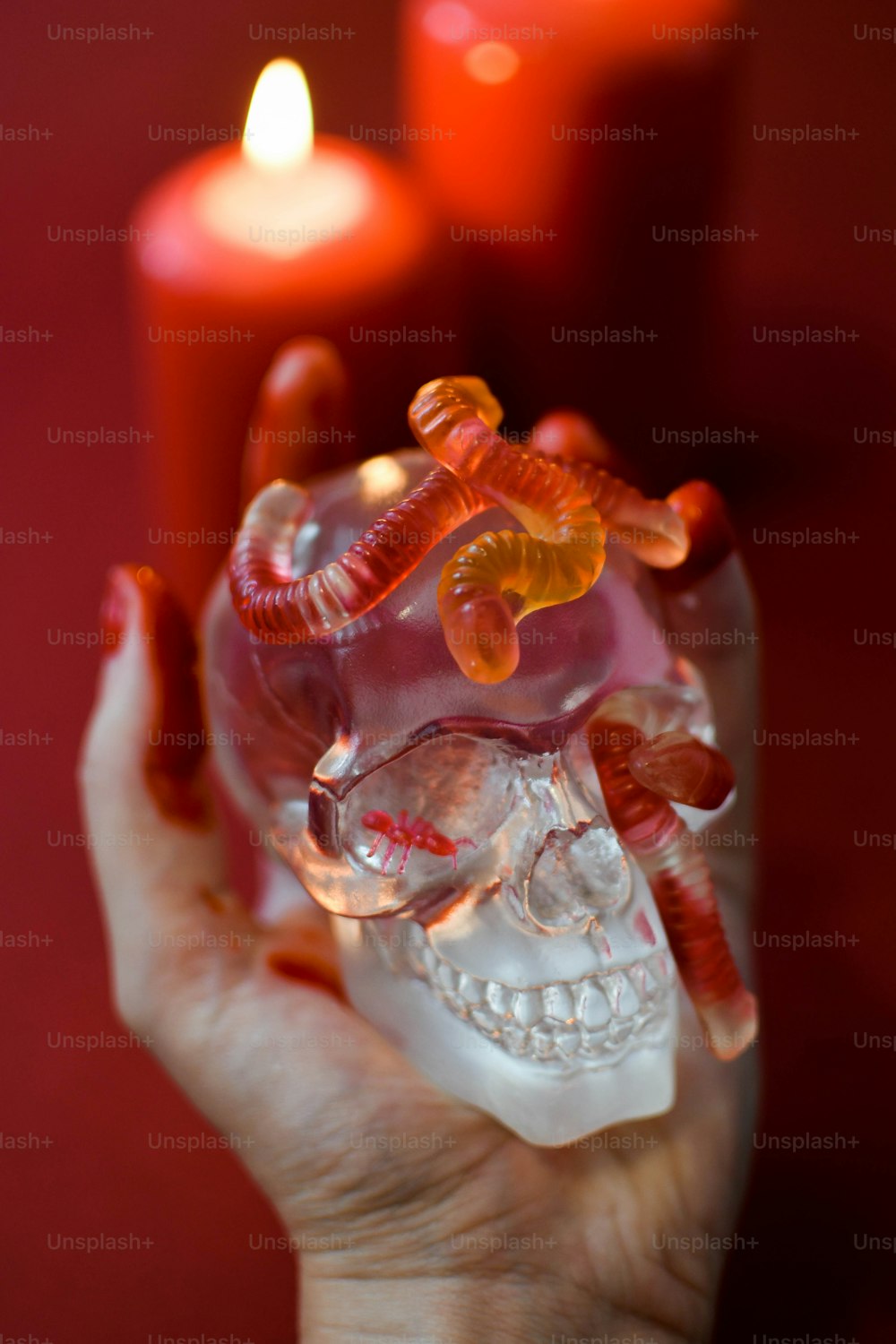uma mão segurando um crânio de vidro com uma vela ao fundo