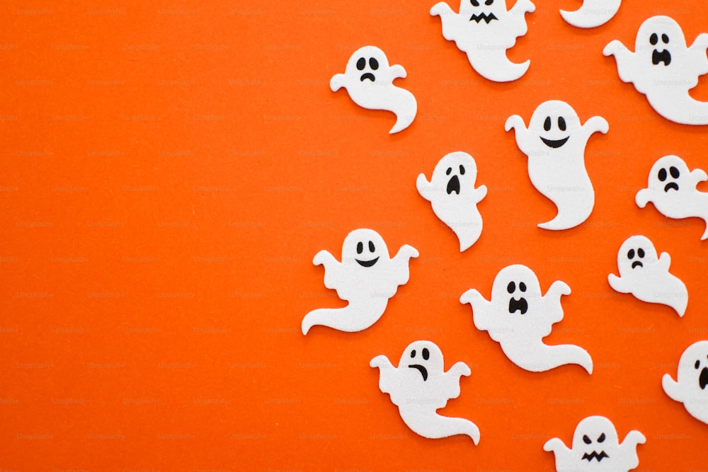 a group of white ghost stickers on an orange background