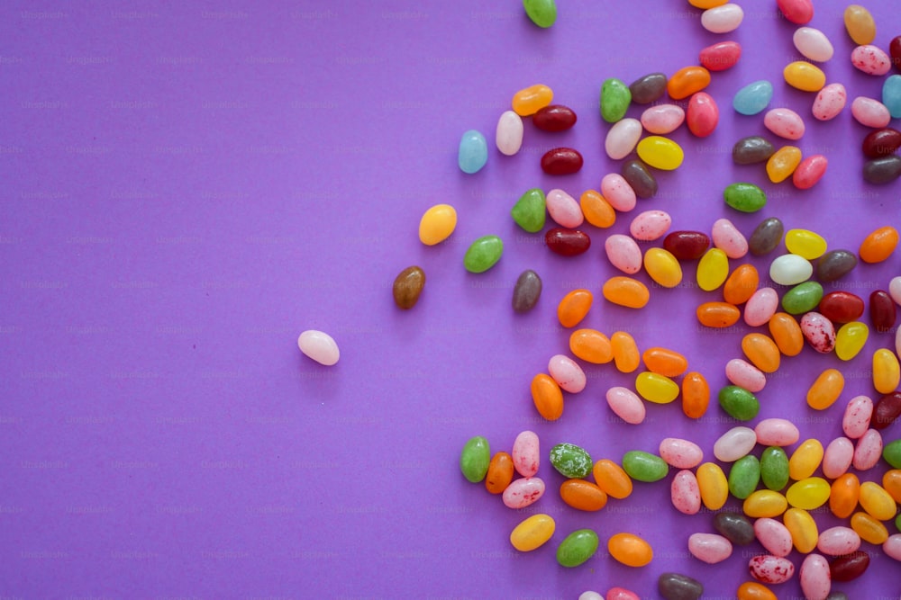 un mucchio di jelly beans seduti sopra una superficie viola