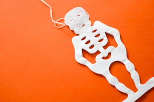 a paper cut out of a skeleton on an orange surface