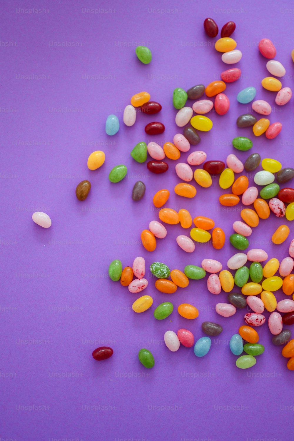 a pile of jelly beans sitting on top of a purple surface