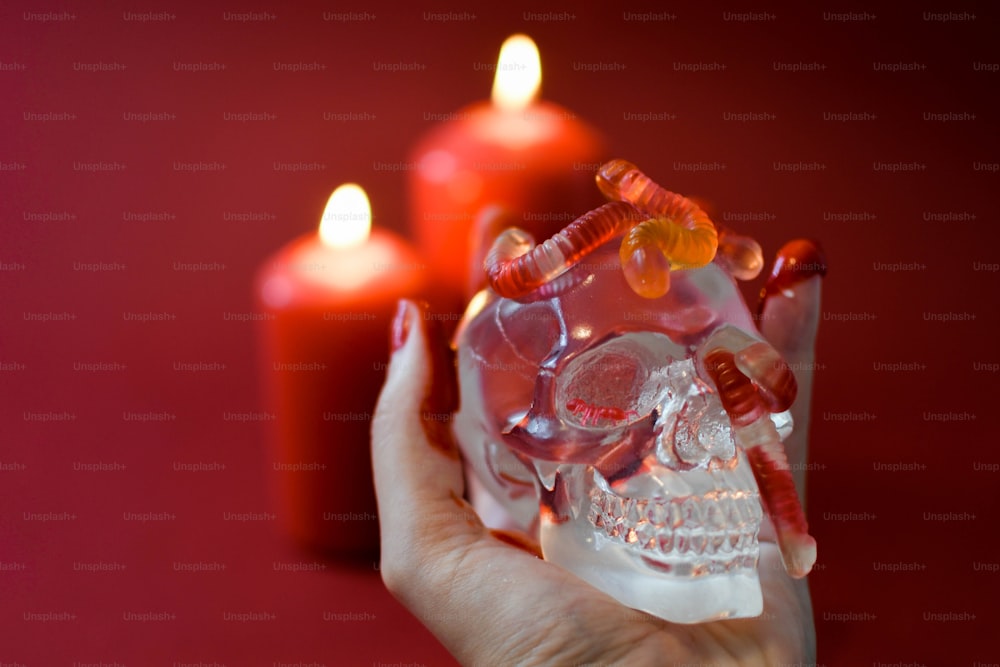 Una mano sosteniendo una calavera de cristal con velas en el fondo