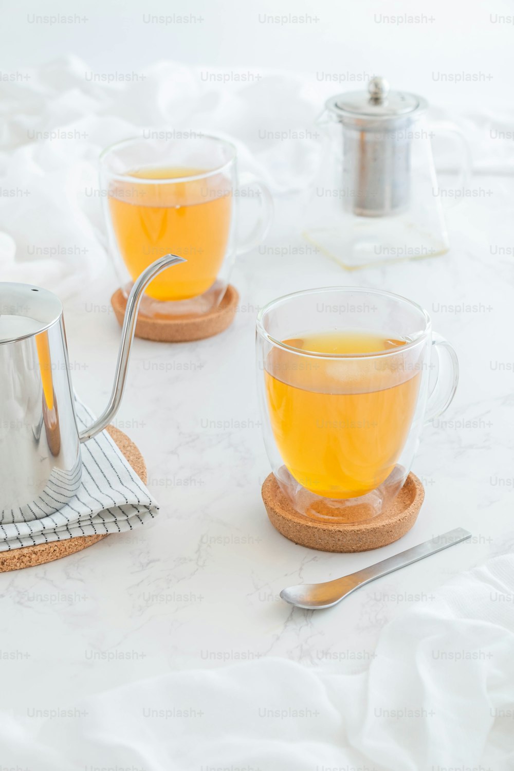 two cups of tea on a table with a tea strainer