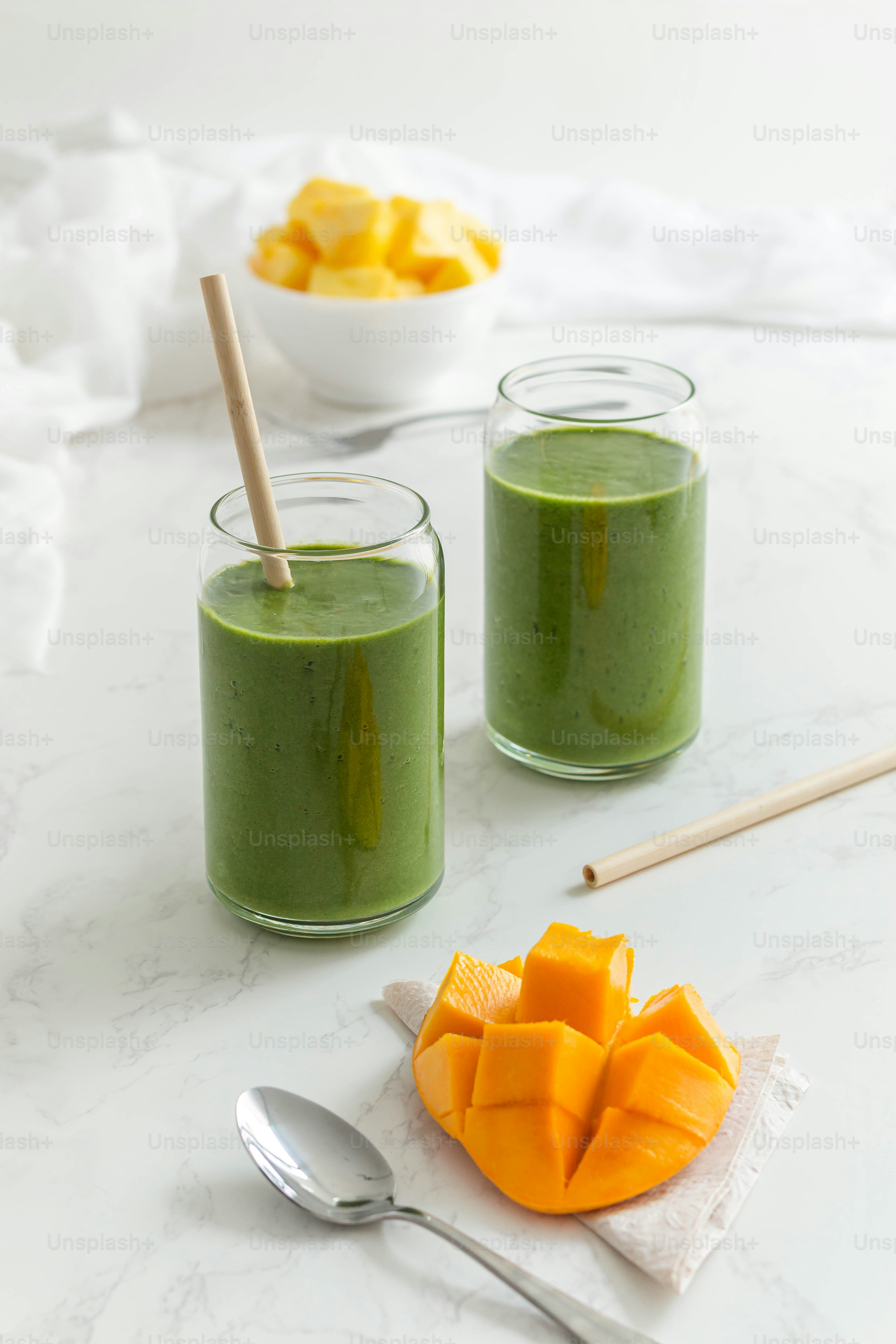 two glasses of green smoothie on a marble table