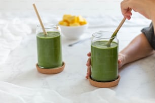 two glasses of green smoothie on a table