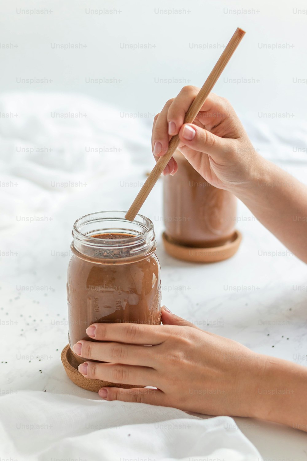 a person holding a wooden spoon over a jar of chocolate