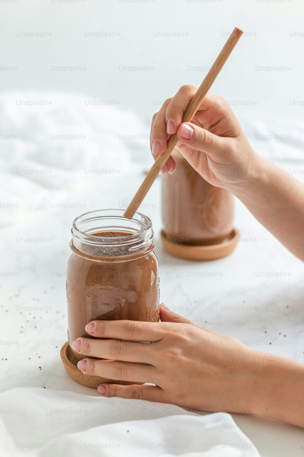 a person holding a wooden spoon over a jar of chocolate