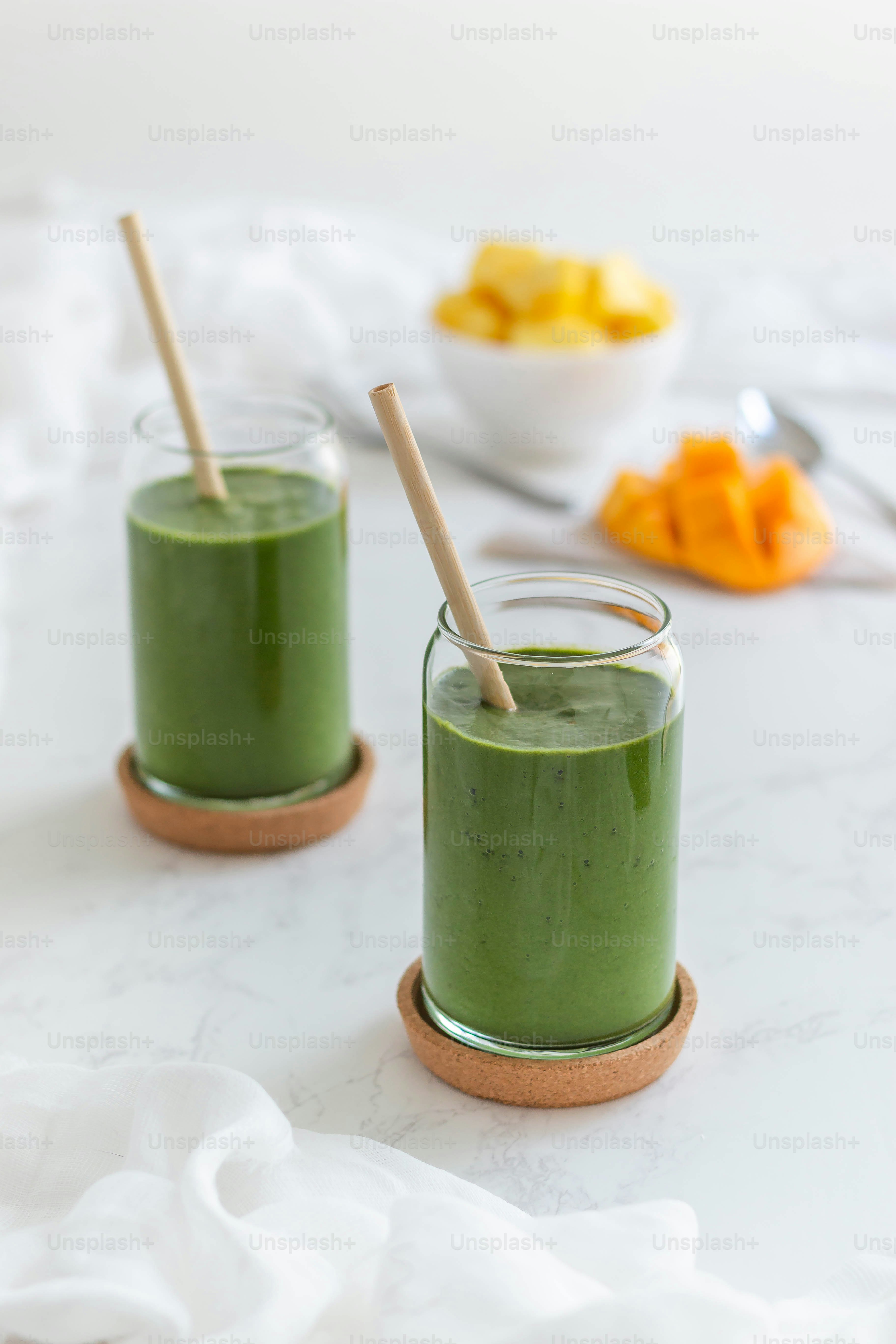 two glasses of green smoothie on a table