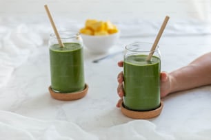 a person holding a glass of green smoothie