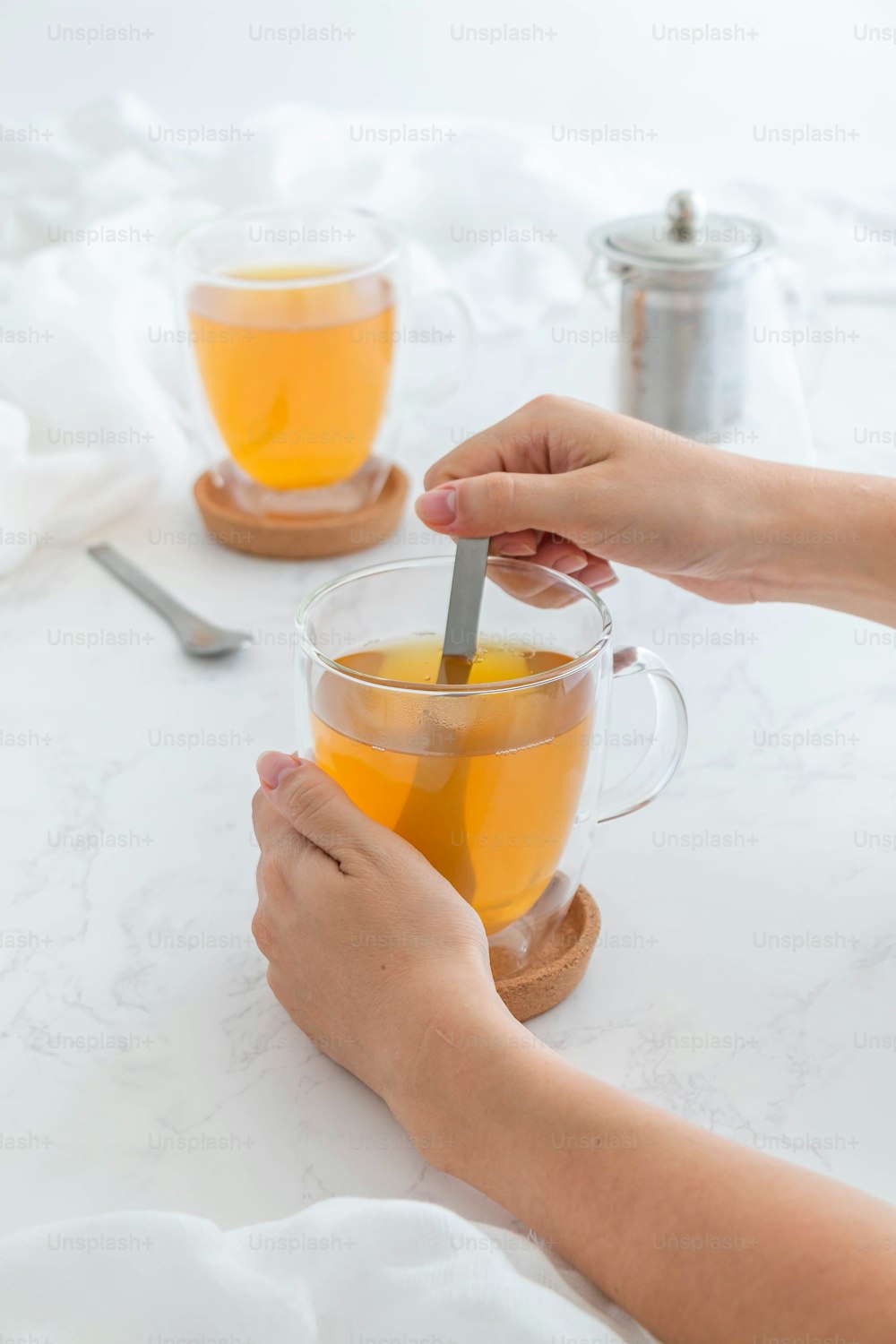 a person holding a spoon in a cup of tea