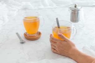 a person holding a cup of tea on a table