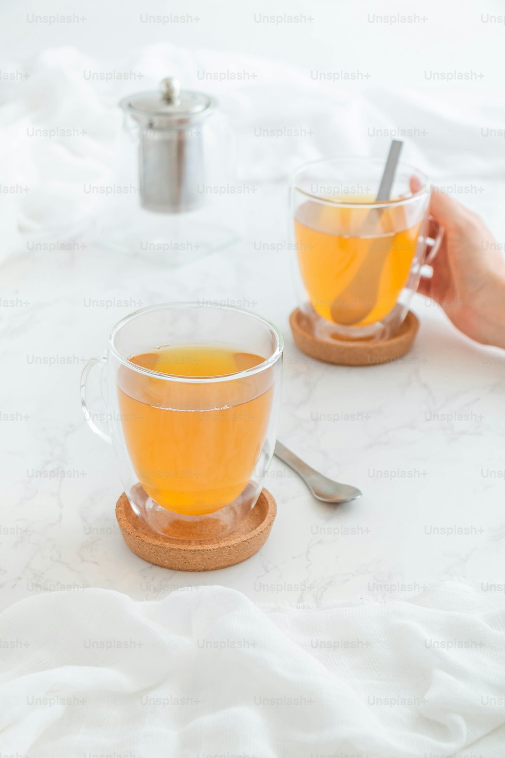 two cups of tea on a table with a spoon