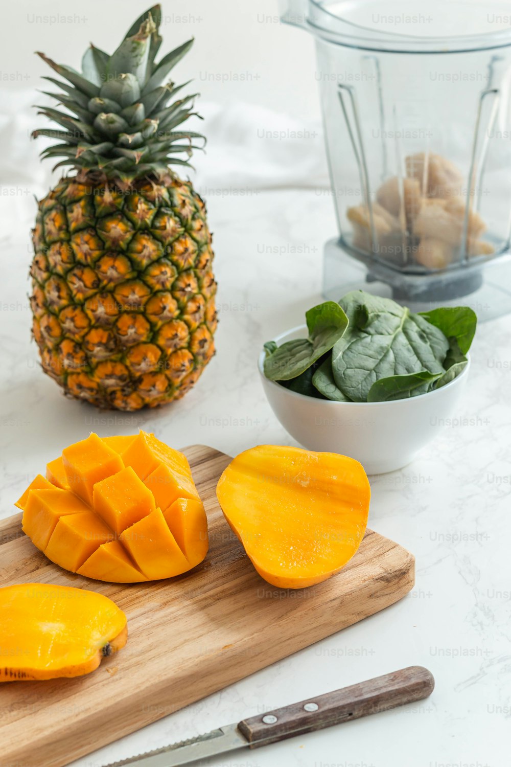 a wooden cutting board topped with sliced mangoes and a pineapple