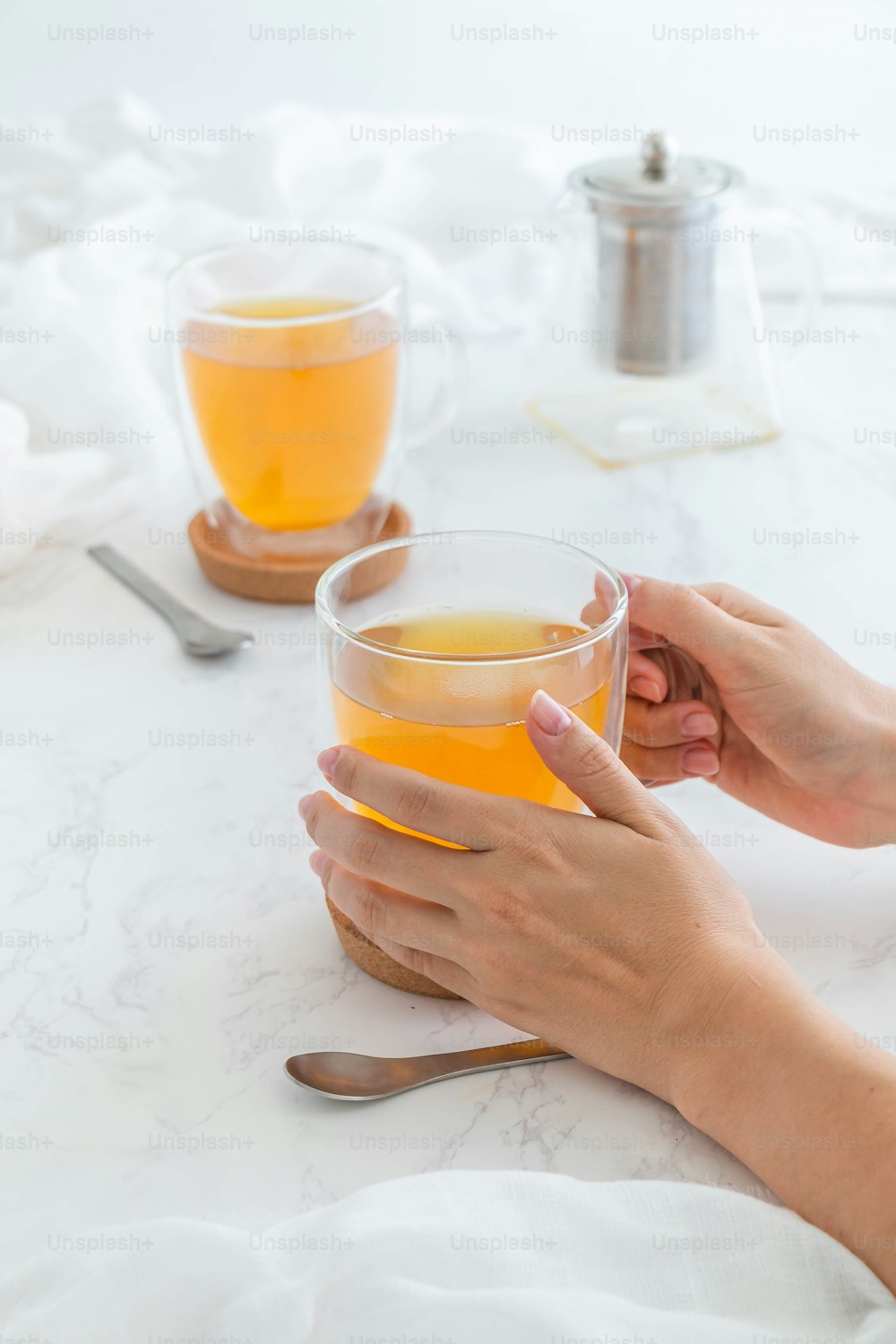 a person holding a glass of tea on a table