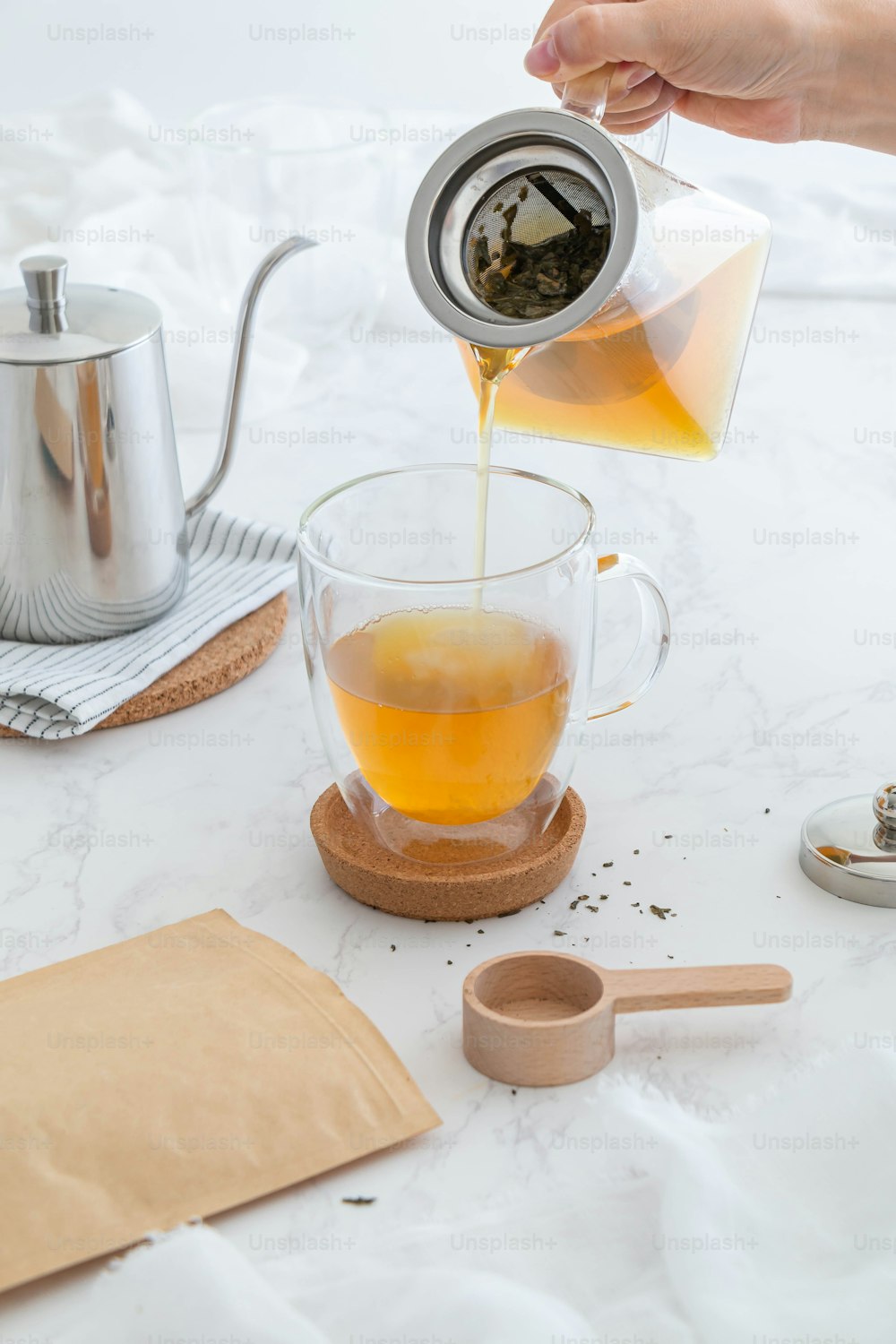 a person pouring tea into a glass cup