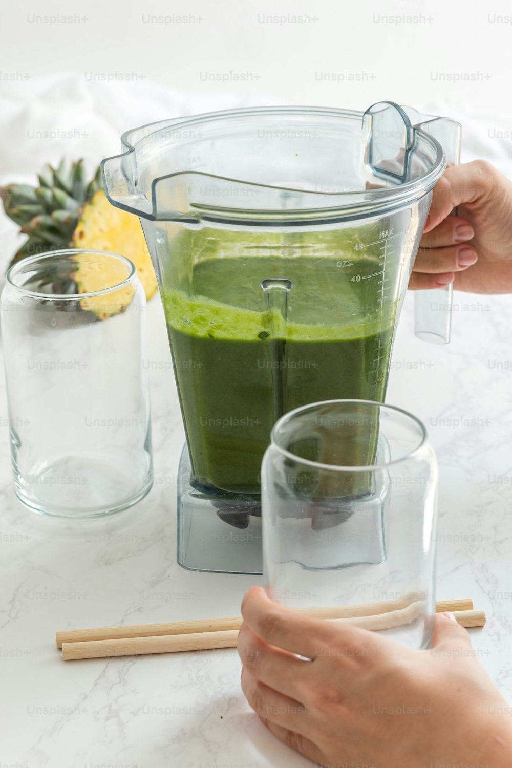 a person pouring a green liquid into a blender