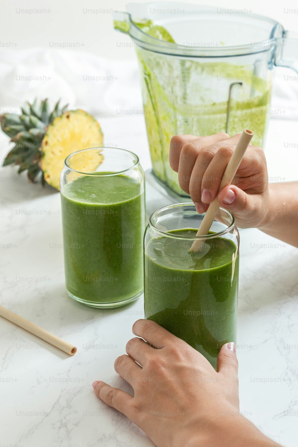a person holding a wooden spoon over a green smoothie