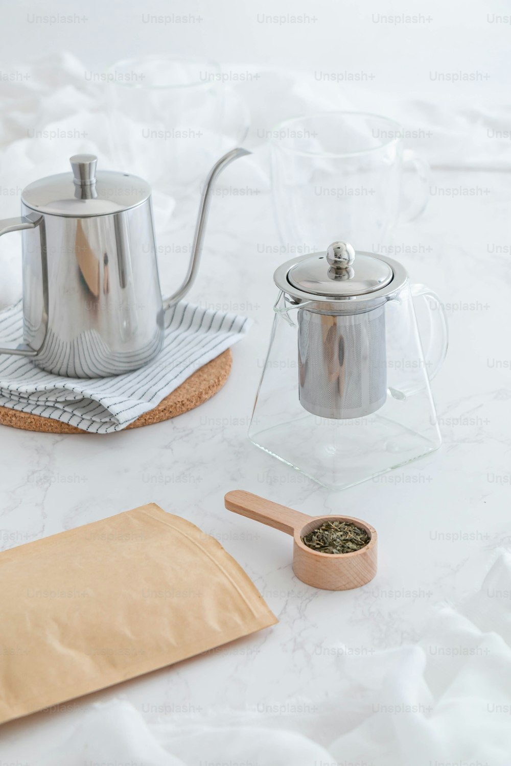 a table with a tea pot, a tea bag, and a wooden spoon
