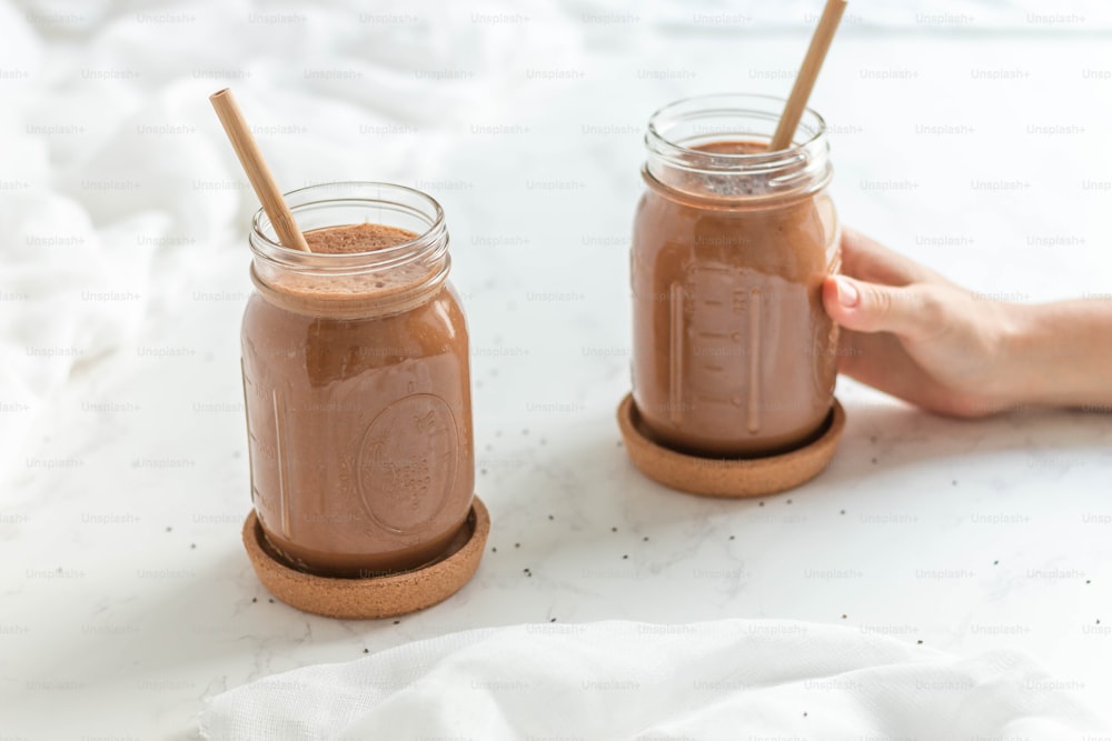 two mason jars filled with chocolate smoothie on a table